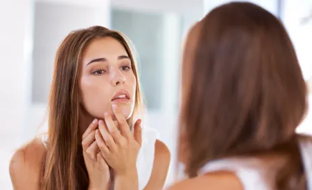 Une femme regarde ses boutons dans le miroir