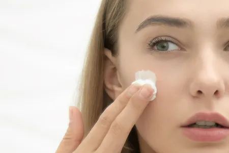 Une femme met de la crème pour peau grasse